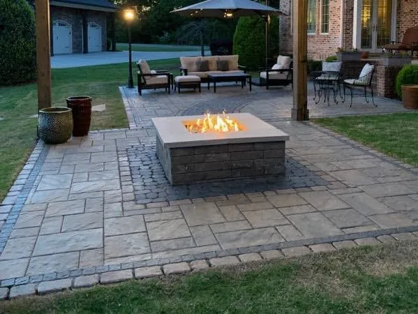 Paver patio with a stone fire pit and cobble border at dusk