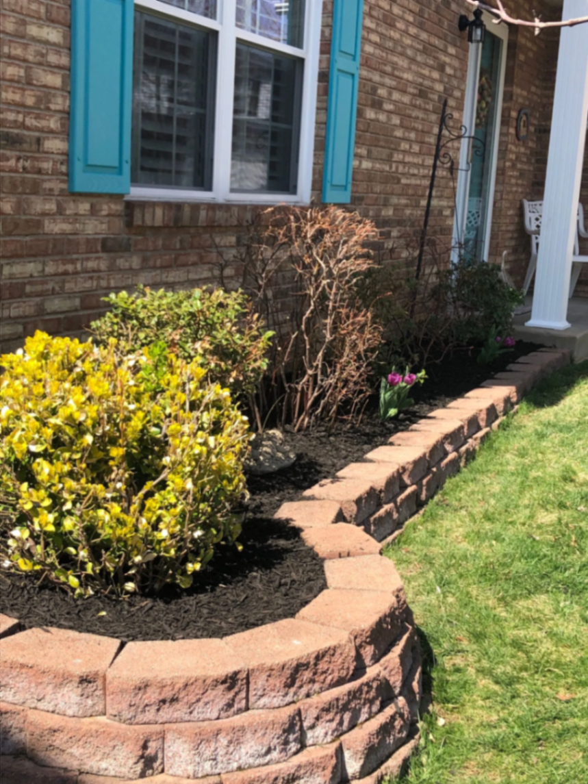 Flower bed with stacked stone border and fresh black mulch